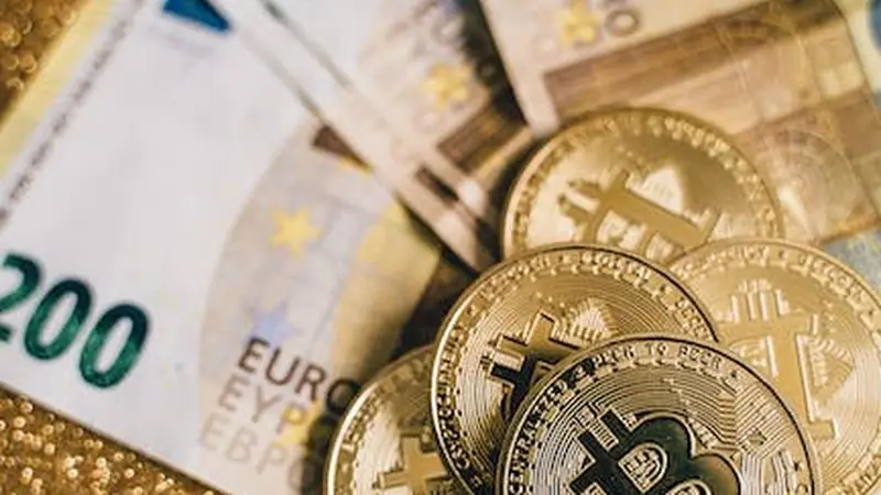 Billetes de euro y monedas de Bitcoin sobre una superficie dorada