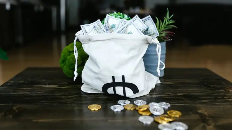 Bolsa con billetes y monedas sobre una mesa