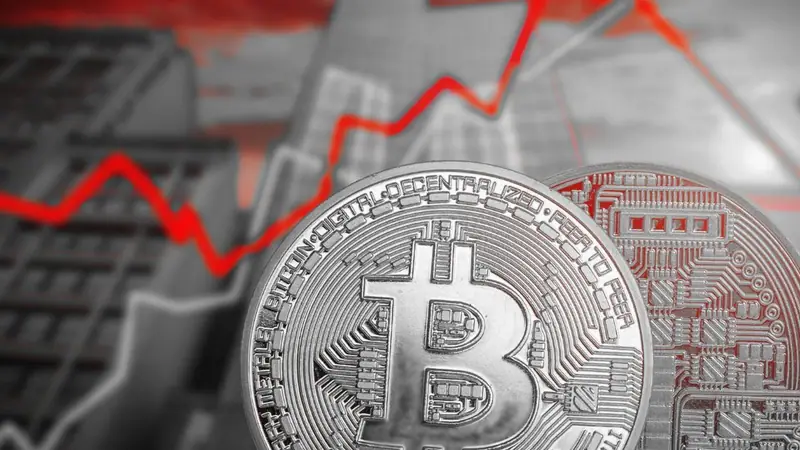 Moneda de Bitcoin sobre un gráfico de precios con tramos rojos